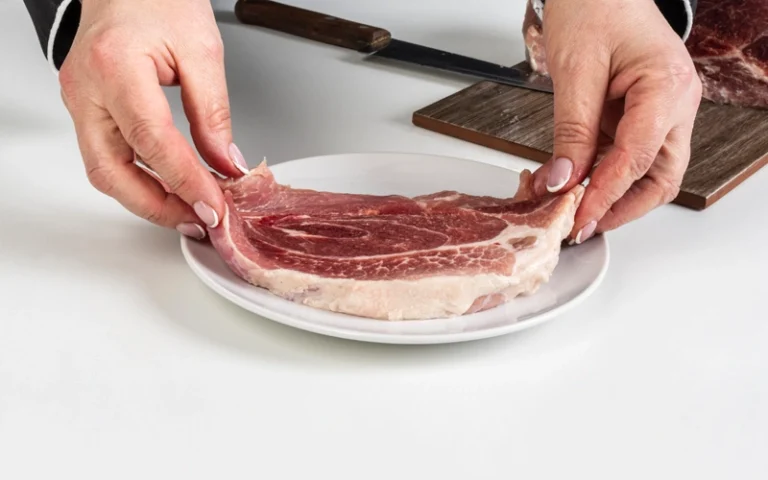 Mains d'une personne disposant un morceau de viande dans une assiette