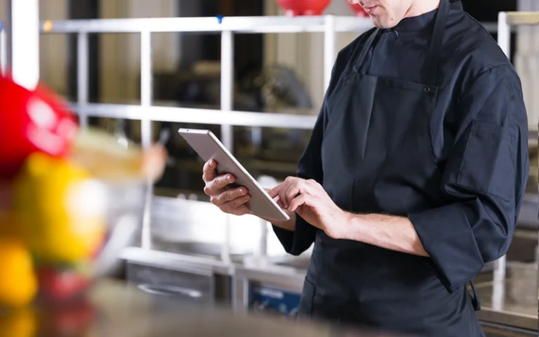 chef de restaurant tenant une tablette dans une cuisine professionnelle