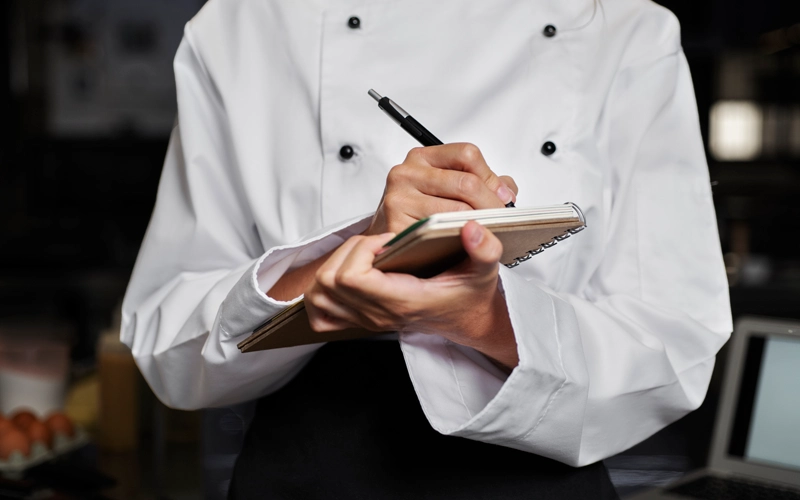 Femme cheffe de cuisine prenant des notes sur son carnet